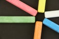 Six colored children crayons on black background, blue red green yellow orange white, top view Royalty Free Stock Photo