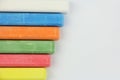 Six colored children crayons on white background, on left side, blue red green yellow orange white, top view Royalty Free Stock Photo