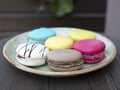 Six colored macarons on the plate. Meringue-y sandwich cookies. Perfect little indulgence