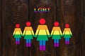 Six colored paper women on wooden background. Lgbt pride concept