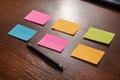 Six colorful sticky notes in two row and pen on brown wooden desk Royalty Free Stock Photo