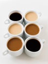 Six cups of coffee of different colors on a white background