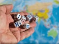 Six dice roll with a man`s hands on world map. World order.d map and money Royalty Free Stock Photo