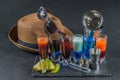 six different colored shot drinks, lined up on a black stone plate, ice cubes in shaker and ice tongs, lemon and lime, brown Royalty Free Stock Photo