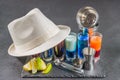 six different colored shot drinks, lined up on a black stone plate, ice cubes in shaker and ice tongs, lemon and lime, white hat Royalty Free Stock Photo