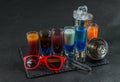 six different colored shot drinks, lined up on a black stone plate, ice cubes in shaker and ice tongs, party set Royalty Free Stock Photo