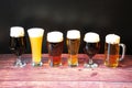 Six different glasses of beer with six different types of beer with froth stand in a row on a wooden table Royalty Free Stock Photo
