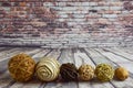 Six different types, colors and composition of wicker decorative balls lie in a row on a wooden old background and a brick wall Royalty Free Stock Photo