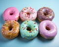 six donuts with frosting and sprinkles on a blue surface