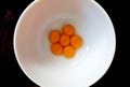 Six egg yolks in a white bowl, from above