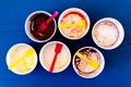 Six empty messy ice cream paper cups with yellow and red plastic