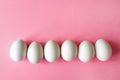 Six empty white chicken eggs beside on a pale pink background