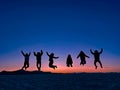 six friends jumping with bluish skyline at sunset