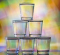 Six glasses stacked by a tower on a multi-colored background Royalty Free Stock Photo