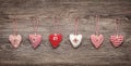 six hand-sewn fabric hearts hang on a string in front of a wooden board. rustic decoration concept