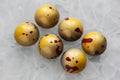 Handmade chocolate candies with yellow shining coating with red drops in the form of a hemisphere on a white matte glass backgroun Royalty Free Stock Photo