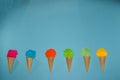 six ice cream, each with a scoop of ice cream made of paper of different colors, blue background Royalty Free Stock Photo