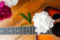 Six metal strings on the neck of an acoustic guitar and lush multicolored fresh peony flowers on wooden boards, close-up, top view