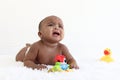 A six month crawling African American baby playing with yellow duck toy on fluffy white rug, happy smiling adorable sweet little Royalty Free Stock Photo