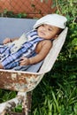 Six month old baby fun concept lying on wheel barrel as if tired from working too hard. Chilling out. Royalty Free Stock Photo