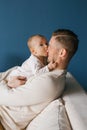 A six-month-old baby son in the arms of his happy father, trying to bite his nose. The child is teething Royalty Free Stock Photo