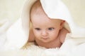 Six months old baby with a towel after taking a bath, in bed at home. Little baby under a white towel