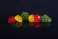 Six multi-colored fruit-paste sweets on the black reflecting su Royalty Free Stock Photo