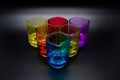 Six multicolored shot glasses placed in triangle on black background