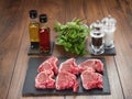 Six raw lamb chops on a slate plate, Infused oils , herbs, salt and pepper shaker on a wooden table surface Royalty Free Stock Photo