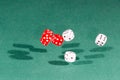 Six red and white dices falling on a green table