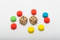 Six-sided dice and circular wooden chips of different colors, red, green, blue, yellow for use in board games such as parcheesi Royalty Free Stock Photo