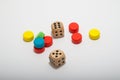 Six-sided dice and circular wooden chips of different colors, red, green, blue, yellow for use in board games such as parcheesi