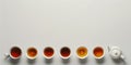 Six tea cups, tea shades, teapot, white background. Generative AI Royalty Free Stock Photo