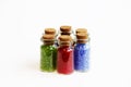 Six tiny glass bottles with a cork stopper, filled with a rainbow colours of beads, on a white background. Royalty Free Stock Photo