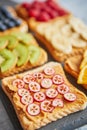 Six toasts with peanut butter, fresh fruits on a grey slate