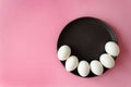 Six white eggs for an inscription on Easter layer, lay on a dark plate in a semicircle, on a rose-colored background Royalty Free Stock Photo