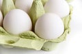 Six white eggs in a open green package, viewed from the top