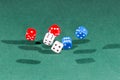 White, red and blue dices falling on a green table Royalty Free Stock Photo