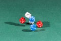 White, red and blue dices falling on a green table Royalty Free Stock Photo