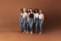 Six women of different ages standing together in studio. Females holding hands and looking at camera