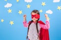 Six year blonde girl dressed like superhero having fun at home. Kid on the background of bright blue wall. Royalty Free Stock Photo