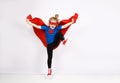 Six year blonde girl dressed like superhero having fun at home. White wall on background