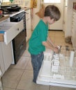 Boy taking silverware out of dishwasher Royalty Free Stock Photo