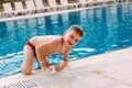 Six-year-old boy in swimming shorts gets out of the outdoor pool on vacation Royalty Free Stock Photo