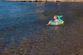 Six-year-old boy swims on an inflatable rubber mattress on the sea