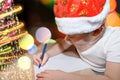 Six year old cute boy with a red christmas cap writing a letter to Santa Claus near the Christmas tree indoors. Bright New Year ba Royalty Free Stock Photo