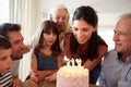 Six year old girl blowing out the candles on birthday cake watched by her mum and family, close up Royalty Free Stock Photo