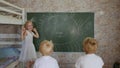 A six year old girl draws on a board in front of her brothers. Royalty Free Stock Photo