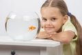 Six year old girl put her head on the handle sitting at the table with an aquarium with goldfish Royalty Free Stock Photo