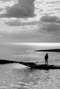 A six year old unrecognisable boy walking along a jetty in the sea black and white photo Royalty Free Stock Photo